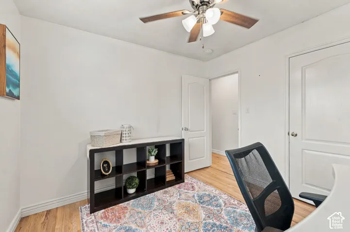 Wood-finish flooring, ceiling fan with integrated lighting, and interior doors with arched-panel detailing