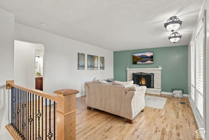 Wood-finish flooring, masonry fireplace, accent wall, and metal spindle railing with wood handrail