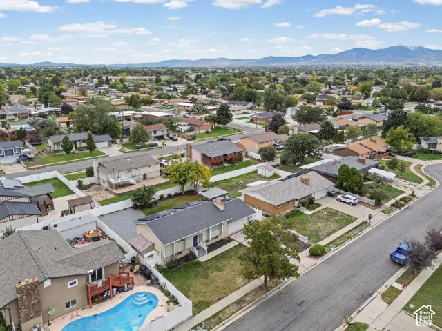 Aerial perspective of a suburban neighborhood featuring residential homes, manicured streetscapes, mature trees, and distant mountain scenery