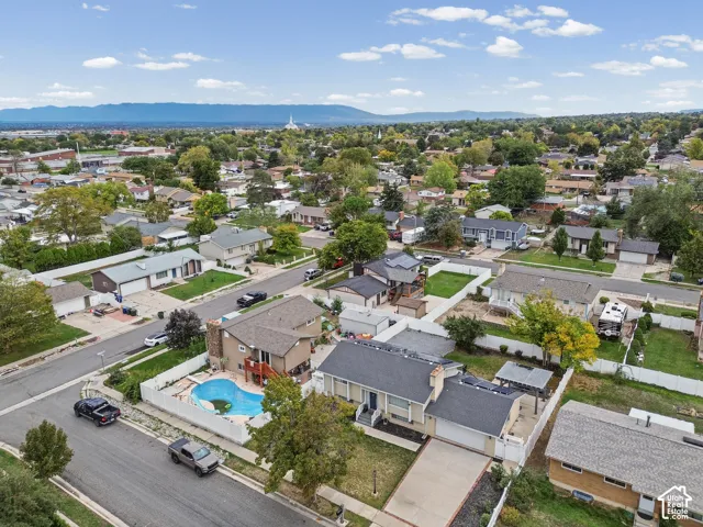 Aerial perspective of a corner lot property featuring an in-ground swimming pool, white privacy fencing, a multi-level deck, and an attached two-car garage