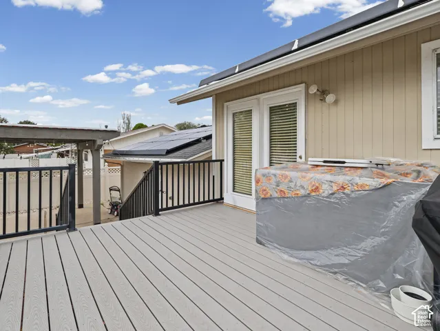 Composite deck with black metal railing, dual-pane French doors, and roof-mounted solar panels