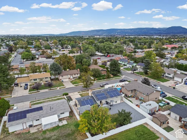 Aerial perspective showcasing a residential lot with solar panel arrays, a fenced perimeter, and a detached structure