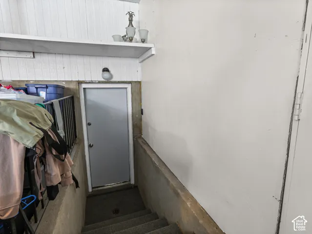 Enclosed stairwell featuring vertical wood paneling, a built-in wall shelf, and a secure exterior-grade door
