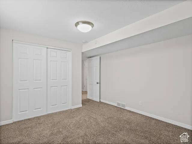 Interior room featuring neutral wall paint, carpeted flooring, a six-panel sliding closet door, a flush-mount ceiling light fixture, and a six-panel interior swing door