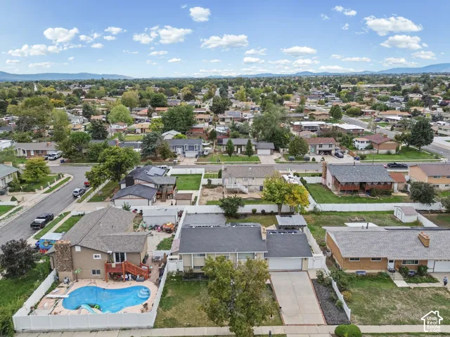 Aerial perspective of a residence featuring a fenced backyard, an in-ground swimming pool, attached two-car garage, concrete driveway, and solar panel arrays