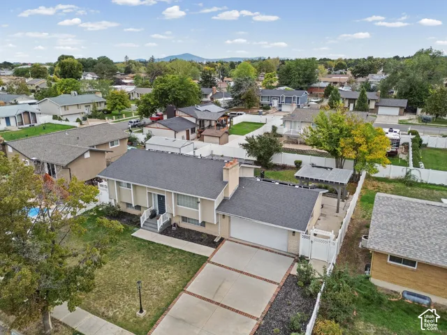 Multi-level exterior featuring a concrete driveway with brick accents, attached two-car garage, pergola-covered patio, and white vinyl privacy fencing