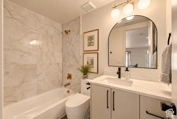 Bathroom featuring floor-to-ceiling large-format stone-patterned tile, an arched wall mirror, a vanity with a stone-top integrated sink, matte black hardware, and metallic-finish shower fixtures