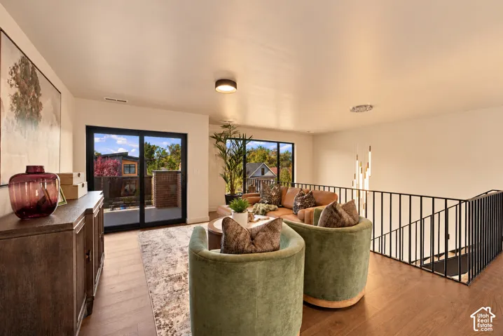 Interior space featuring wood-finish flooring, sliding glass doors, large picture windows, and a matte black metal railing