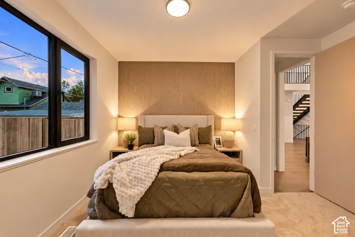 Bedroom featuring large windows with black frames, a textured accent wall, flush-mount lighting, and carpeted flooring