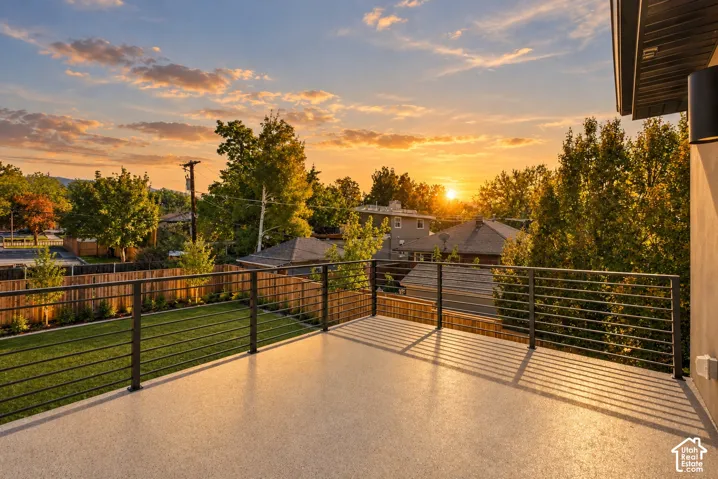 Elevated deck featuring a textured composite surface, horizontal metal cable railing, and a fenced backyard