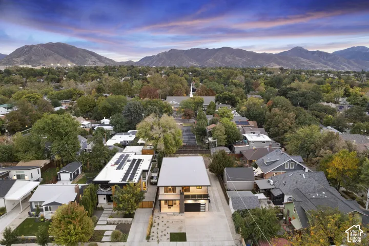 Contemporary two-story exterior featuring a metal roof, integrated balcony, attached two-car garage, and desert-inspired hardscaping set against a mountain backdrop