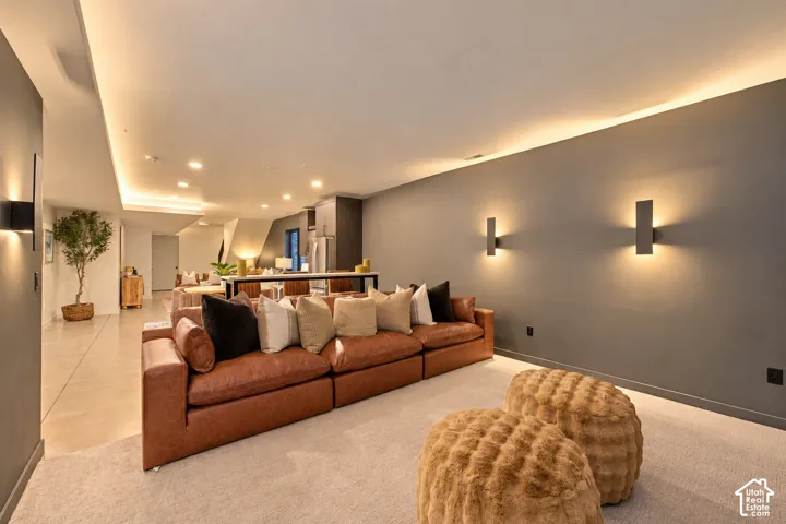 Open-concept interior featuring recessed cove lighting, dual wall-mounted sconces, neutral carpeting, and smooth-finish gray walls