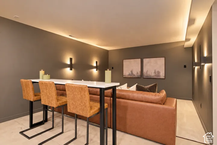 Interior space featuring matte wall finishes, integrated recessed cove lighting, sleek wall-mounted sconces, and neutral-toned carpeting