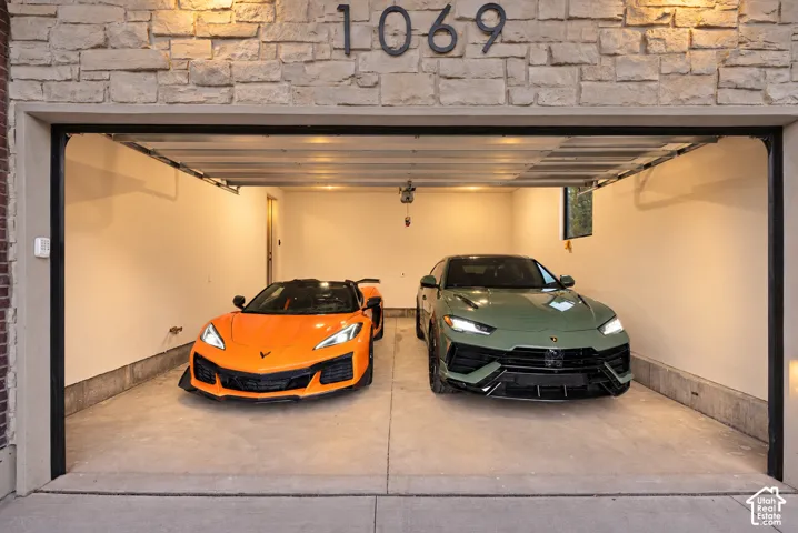 Attached two-car garage featuring stacked stone exterior facade, concrete flooring, and interior lighting