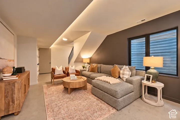 Interior space featuring polished concrete flooring, recessed cove lighting, and a dark accent wall with an inset window