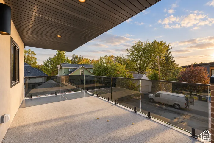 Covered balcony featuring a concrete floor surface, glass panel railing with black hardware, and recessed ceiling lighting