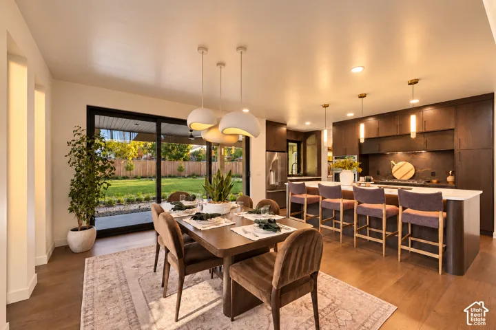 Open-concept kitchen featuring dark wood cabinetry, expansive center island with stone-finish countertop, wood-finish flooring, and multi-pane sliding glass doors