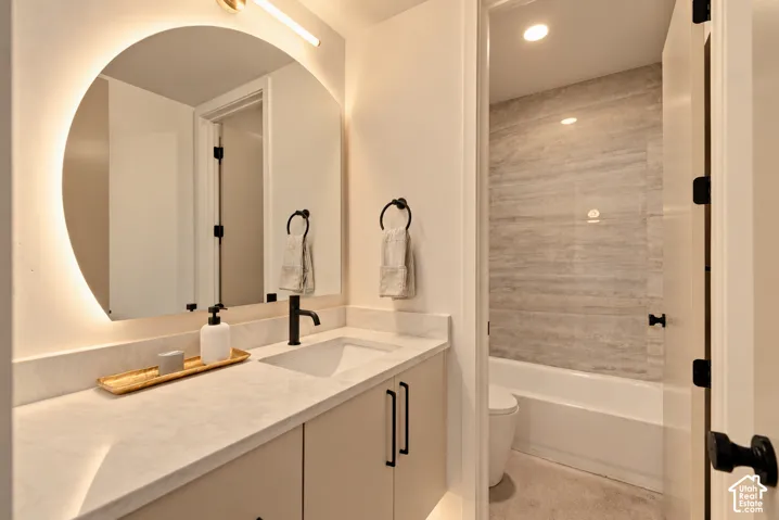 Modern vanity with a composite countertop and integrated rectangular basin, accented by a backlit arched mirror, matte black fixtures, and horizontal-tile tub surround