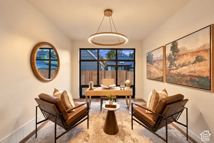 Minimalist room featuring a large, multi-pane black-framed window, circular suspended ring chandelier, and wood-finish flooring