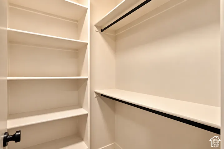 Storage space featuring built-in shelving and dual hanging rods with matte black hardware