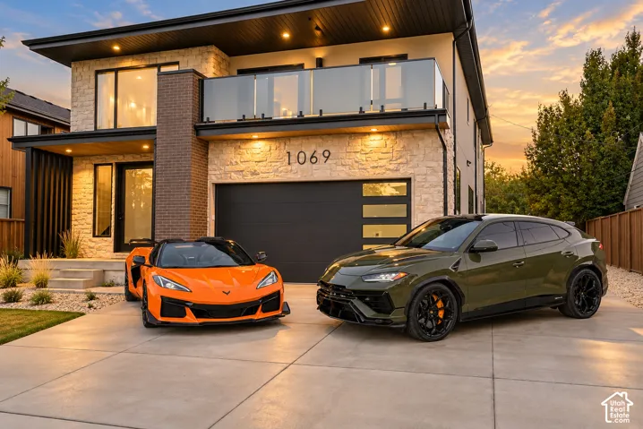 Modern two-story exterior featuring natural stone veneer, dark brick accents, a glass-railed balcony, and a multi-panel garage door with frosted glass inserts