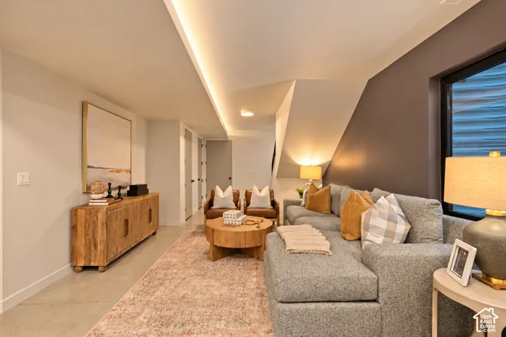 Interior space featuring polished concrete flooring, recessed cove lighting, and a prominent dark accent wall