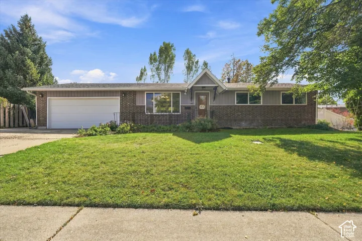 Single-story residence featuring a brick and vertical siding exterior, an attached two-car garage, a gabled front entryway, and a sprawling front lawn