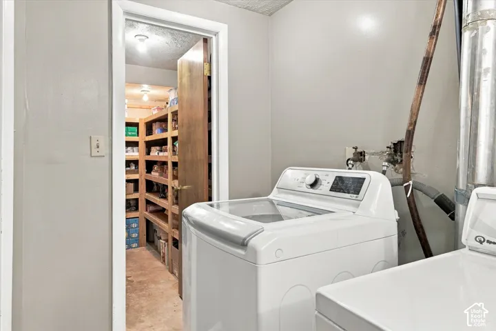 Utility area featuring washer hookups and a walk-in storage room with built-in wooden shelving