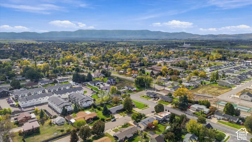 Aerial perspective of the residential community featuring mature trees, paved streets, and a prominent mountain backdrop