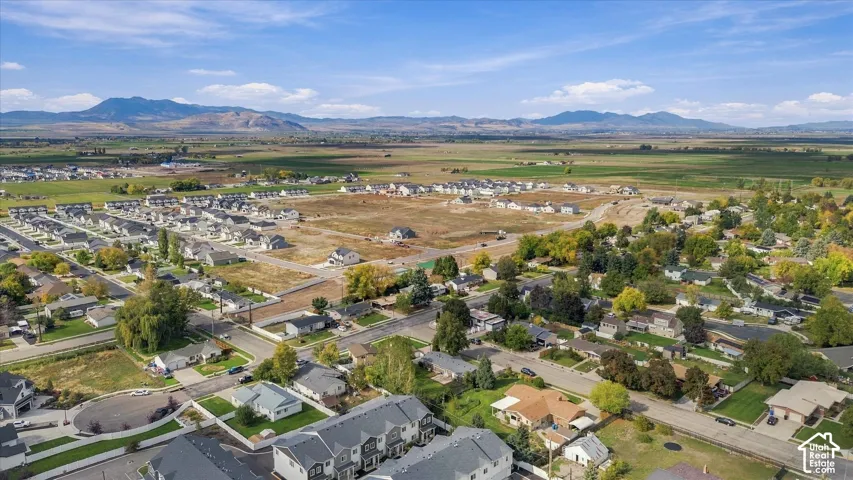 Aerial perspective of a residential neighborhood featuring expansive mountain backdrops, mature trees, and established street infrastructure