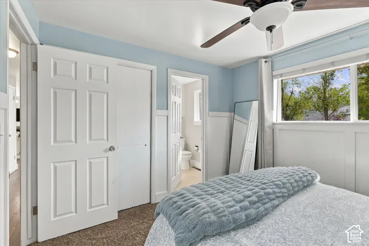 Interior space featuring two-tone wall paint, waist-high wainscoting, carpeted flooring, and a ceiling-mounted light fixture with a fan