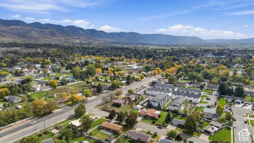 Aerial perspective of the community featuring mature trees, landscaped lawns, and mountain scenery