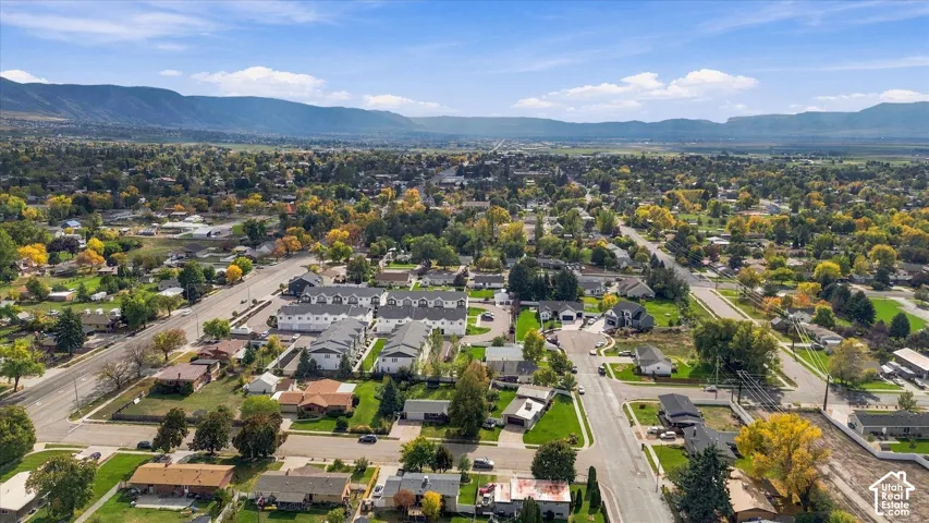 Aerial perspective of a multi-unit residential complex featuring gabled rooflines, neutral exterior siding, and mountain backdrop