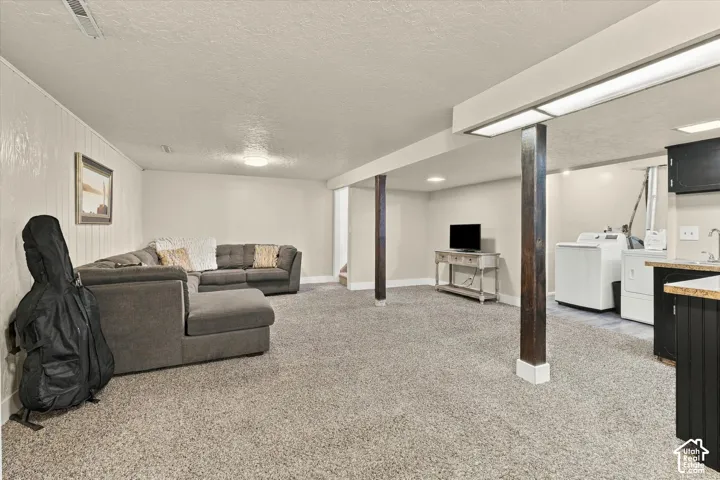Finished interior space featuring carpeted flooring, decorative wood-wrapped support columns, recessed lighting, and a built-in kitchenette area