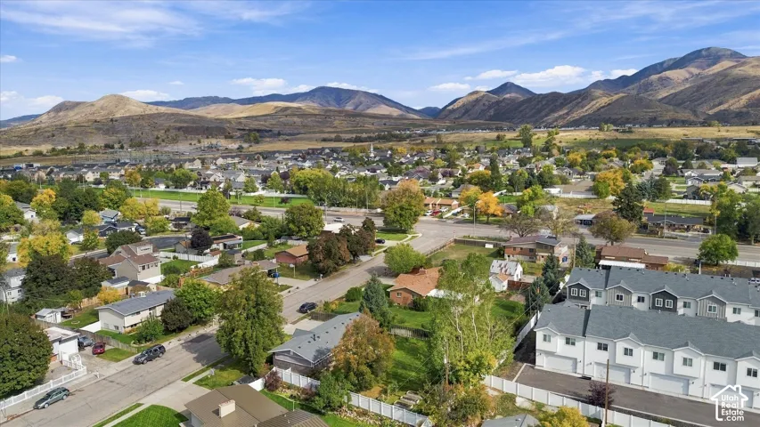 Aerial perspective featuring multi-level residential structures, white vinyl perimeter fencing, and expansive mountain range backdrop