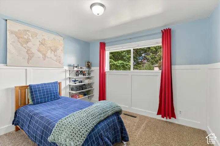 Interior space featuring white board-and-batten wainscoting, wall-to-wall carpeting, large window, and built-in shelving