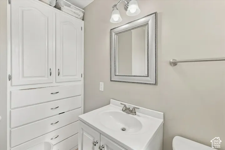 Built-in floor-to-ceiling cabinetry, vanity with integrated basin, polished metal hardware, two-light fixture, and framed wall-mounted mirror