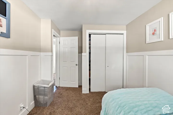 Neutral wall tones accented by white wainscoting, beige carpeting, and white interior doors, including a two-panel sliding closet