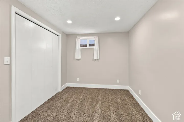 Neutral-toned interior featuring wall-to-wall carpet, recessed lighting, and a bi-fold closet
