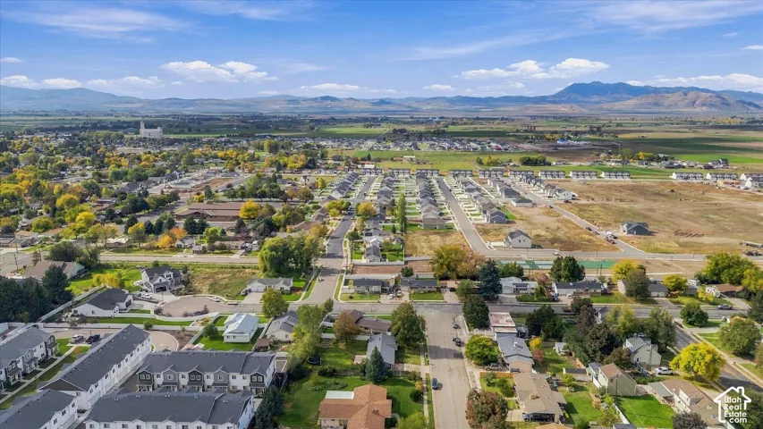 Aerial perspective of a residential neighborhood featuring mature tree-lined streets, established landscaping, and mountain backdrops