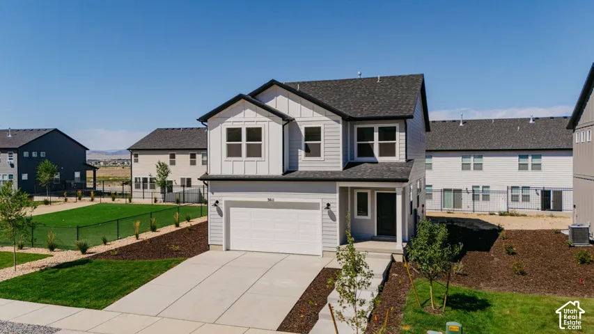Two-story exterior featuring light gray horizontal siding, white board-and-batten accents, a covered entryway, an attached two-car garage, and asphalt shingle roofing