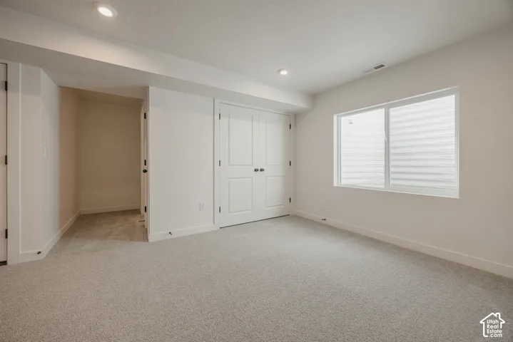 Neutral-toned wall-to-wall carpeting, double-panel closet doors, recessed lighting, and a window egress
