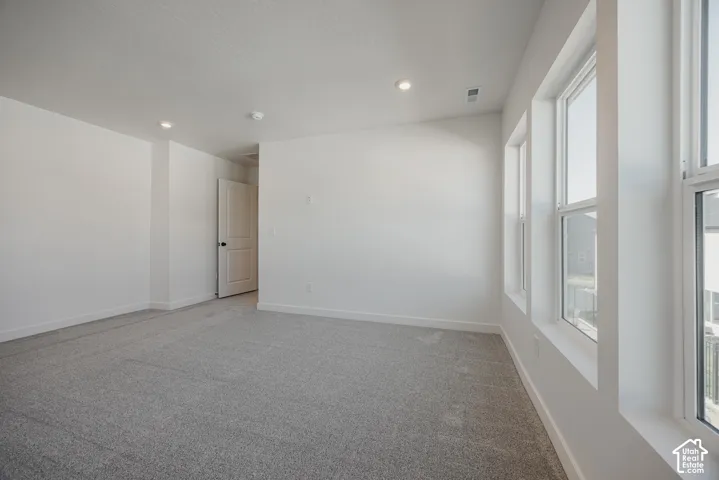 Neutral-toned wall-to-wall carpeting, crisp white interior walls, recessed ceiling lighting, and multiple tall windows