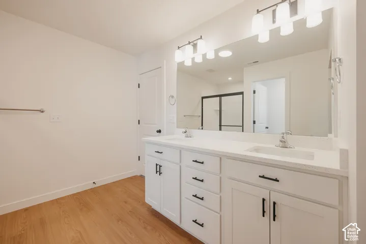 Double vanity featuring a light-toned solid surface countertop, white shaker-style cabinetry, matte black hardware, and two multi-bulb light fixtures