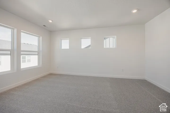 Room featuring neutral wall-to-wall carpeting, multiple tall windows, square transom windows, and recessed lighting