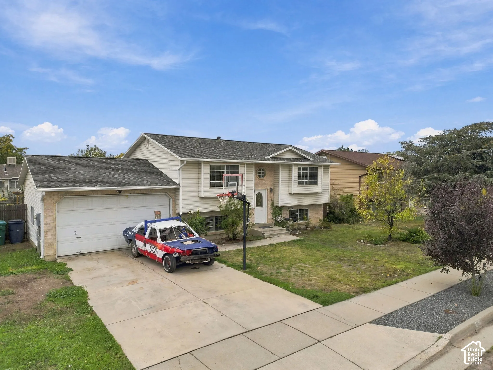 Split-level exterior featuring horizontal siding, stone veneer accents, a shingled roof, and an attached two-car garage