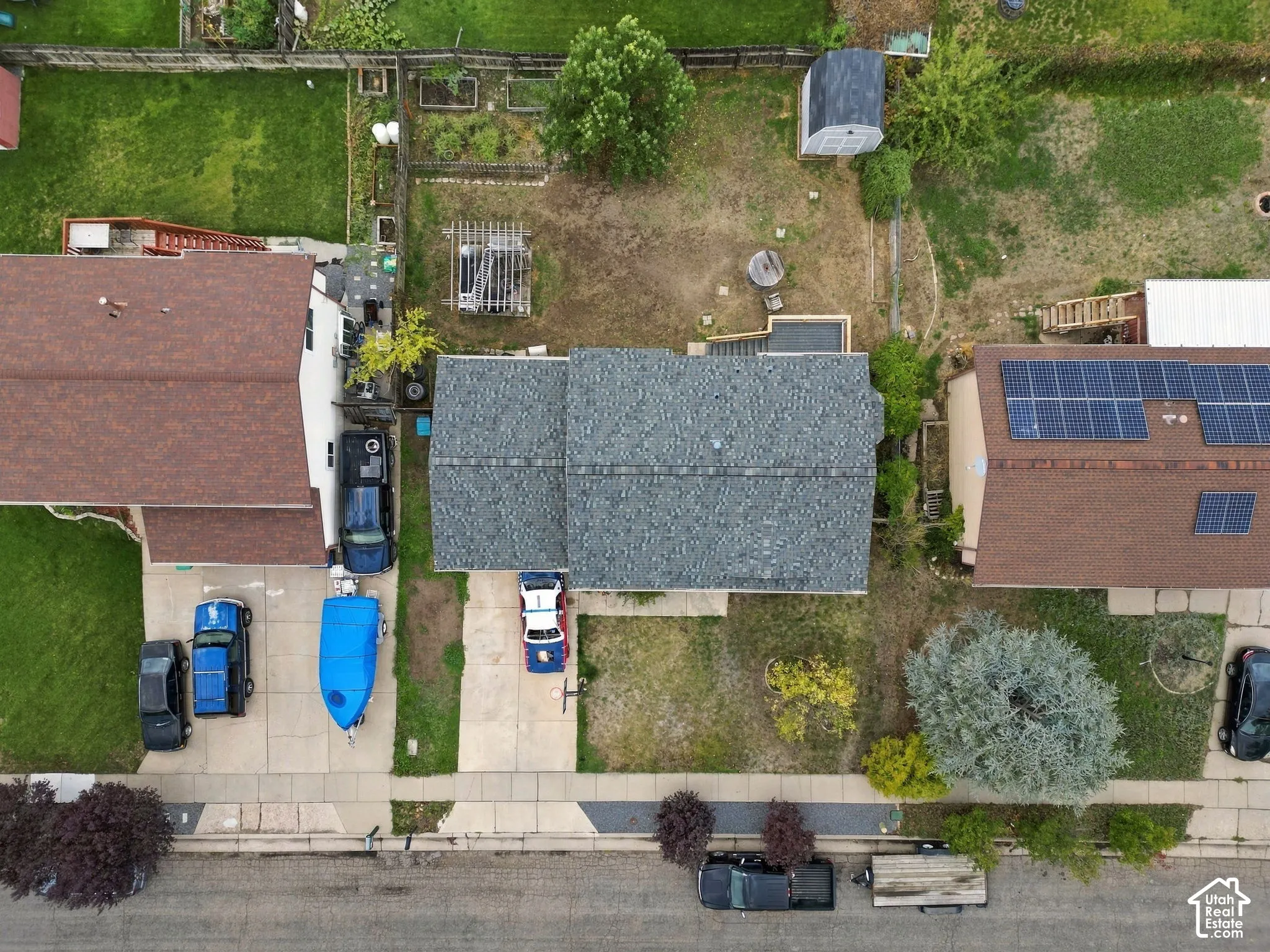 Aerial view of residential lot featuring a concrete driveway, grass yard area, and a wooden pergola