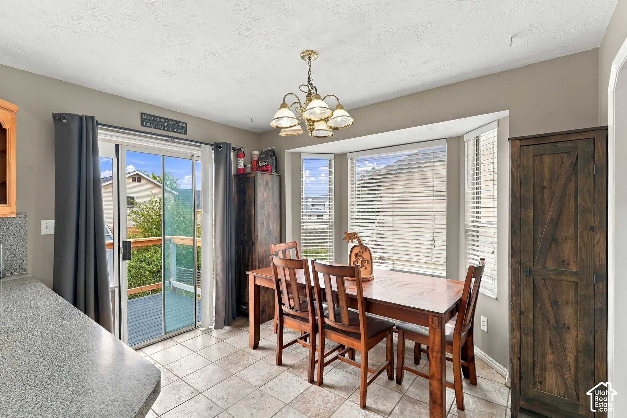 Dining area featuring ceramic tile flooring, a multi-light chandelier, a triple-pane bay window, and a sliding glass door providing exterior access