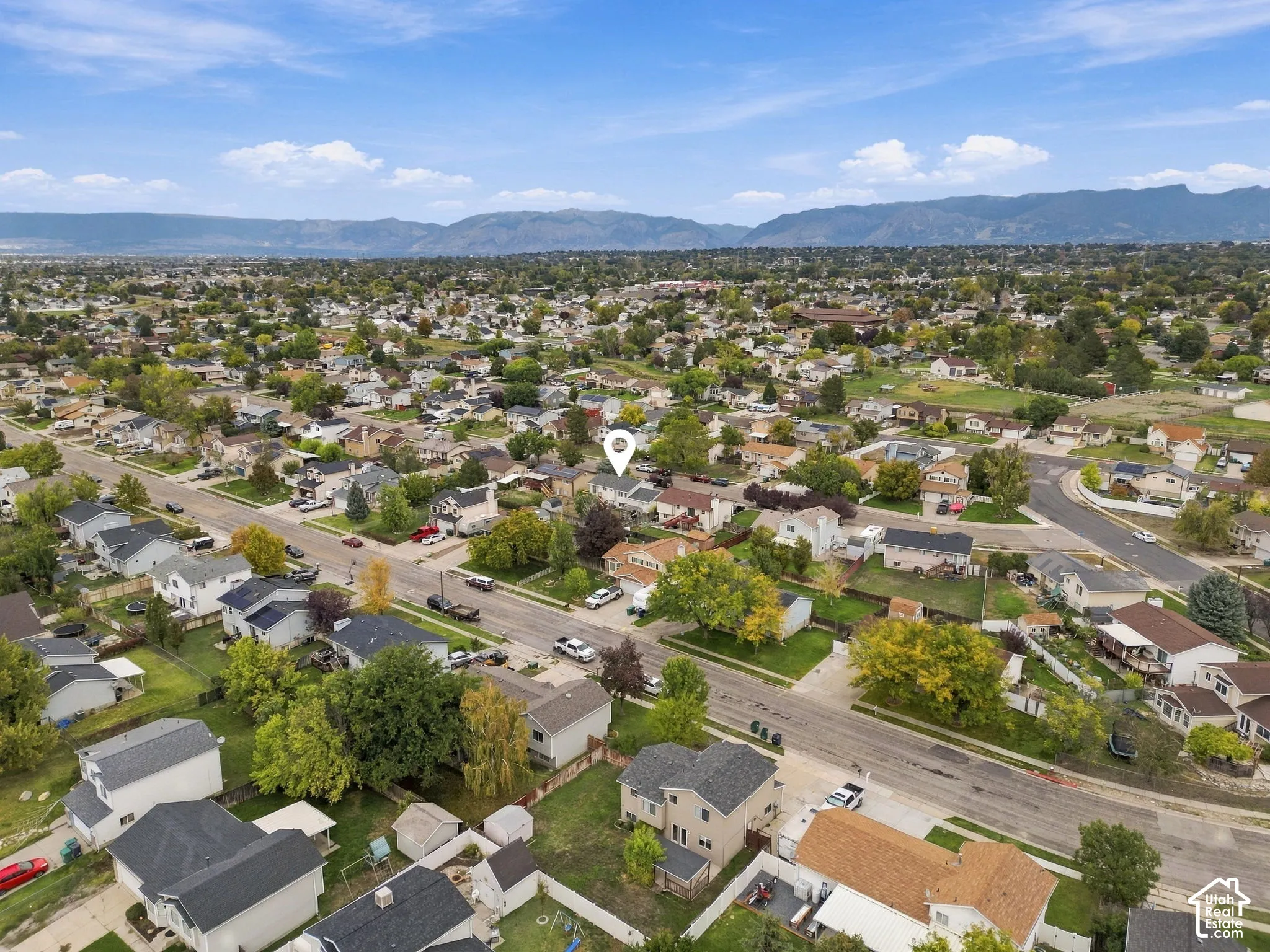 Aerial perspective of a residential property situated in a suburban setting with mountainous terrain on the horizon