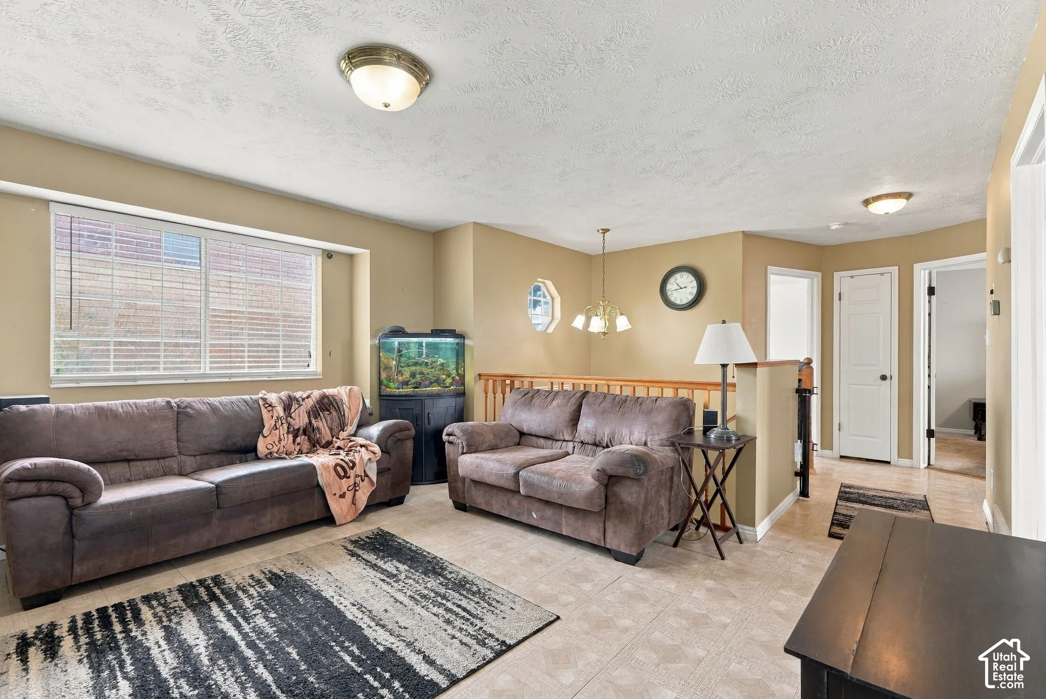 Living area featuring tile flooring, a large picture window, a decorative multi-pane accent window, and a wood-railing partition